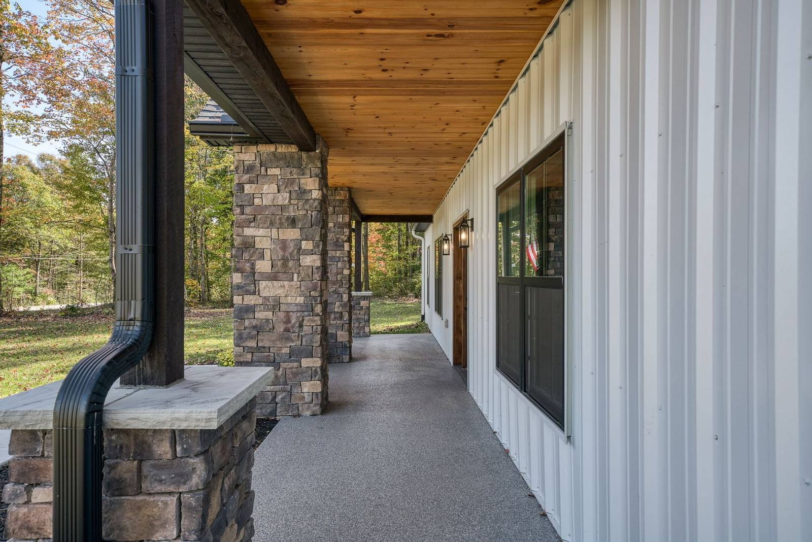 Long covered side porch with stone columns and wood ceiling